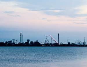 Large body of water with amusement park rides in the background lit up in colored lights