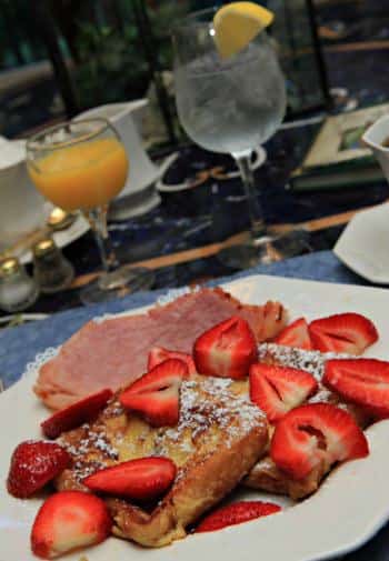 White breakfast plate topped with French toast, fresh strawberries, and ham