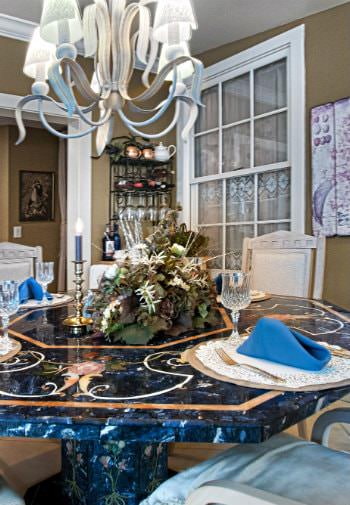 Blue marble octagonal dining table with chairs, chandelier, and centerpiece set for a meal